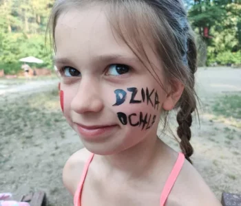 Dziewczynka z napisem Dzika Ochla namalowanym na policzku podczas plażówki dla dzieci
